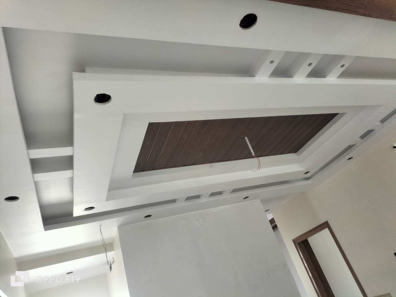 Recessed POP ceiling design with a wooden panel insert and spotlight cutouts